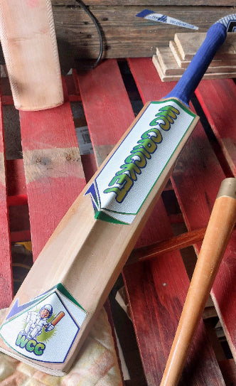 Wooden cricket bat with WCC branding on a wooden surface