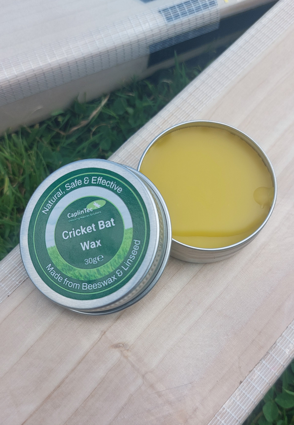 Tin of natural cricket bat wax on English willow bat showing yellow beeswax balm to nourish and protect