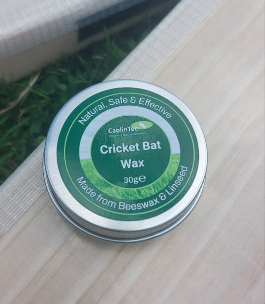 WC Cricket CaplinTec 30g tin of natural cricket bat wax on willow bat and grass background