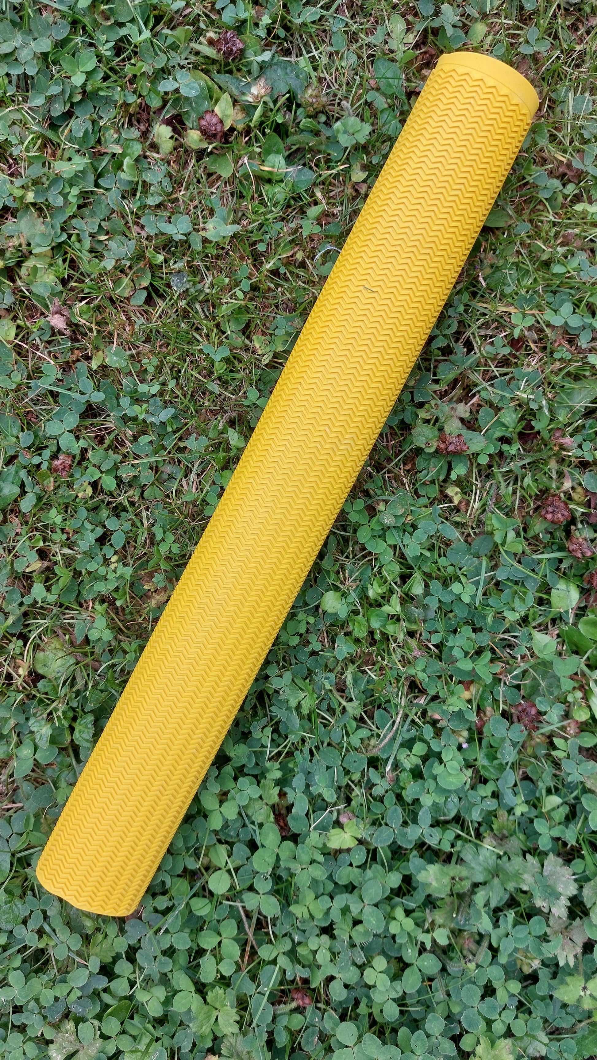 WC Cricket yellow chevron cricket bat grip rolled on grass showing textured zigzag pattern for bat restoration
